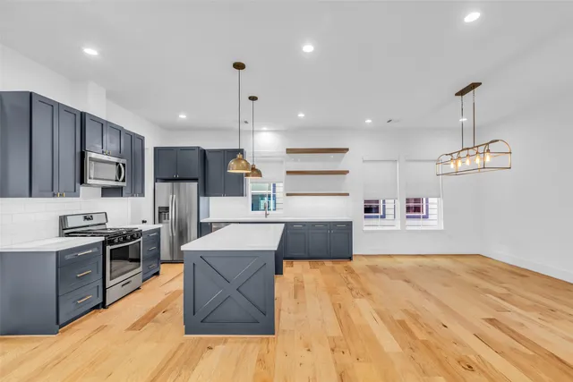 a large kitchen with stainless steel appliances kitchen island a large counter top a sink stainless steel appliances and cabinets