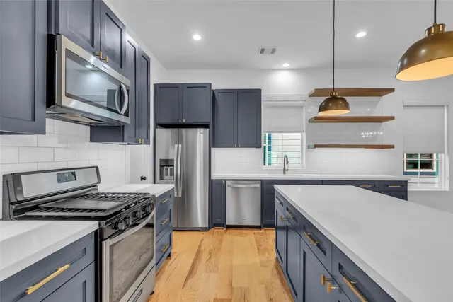 a kitchen with stainless steel appliances granite countertop a sink a stove and a refrigerator