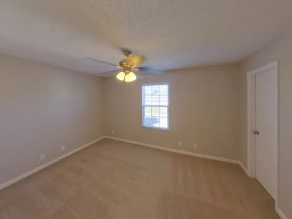 an empty room with windows and chandelier fan