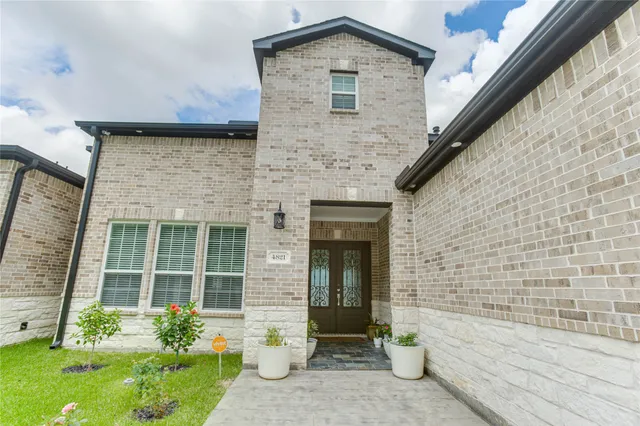 a front view of a house with a yard and potted plants