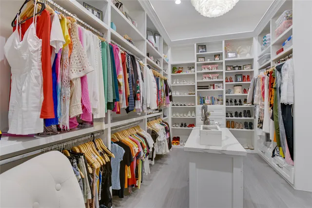 a view of walk in closet with clothes and shoes