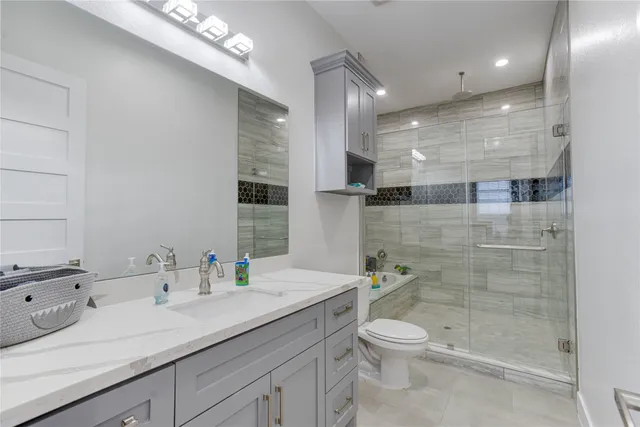 a bathroom with a granite countertop sink a toilet a mirror and shower