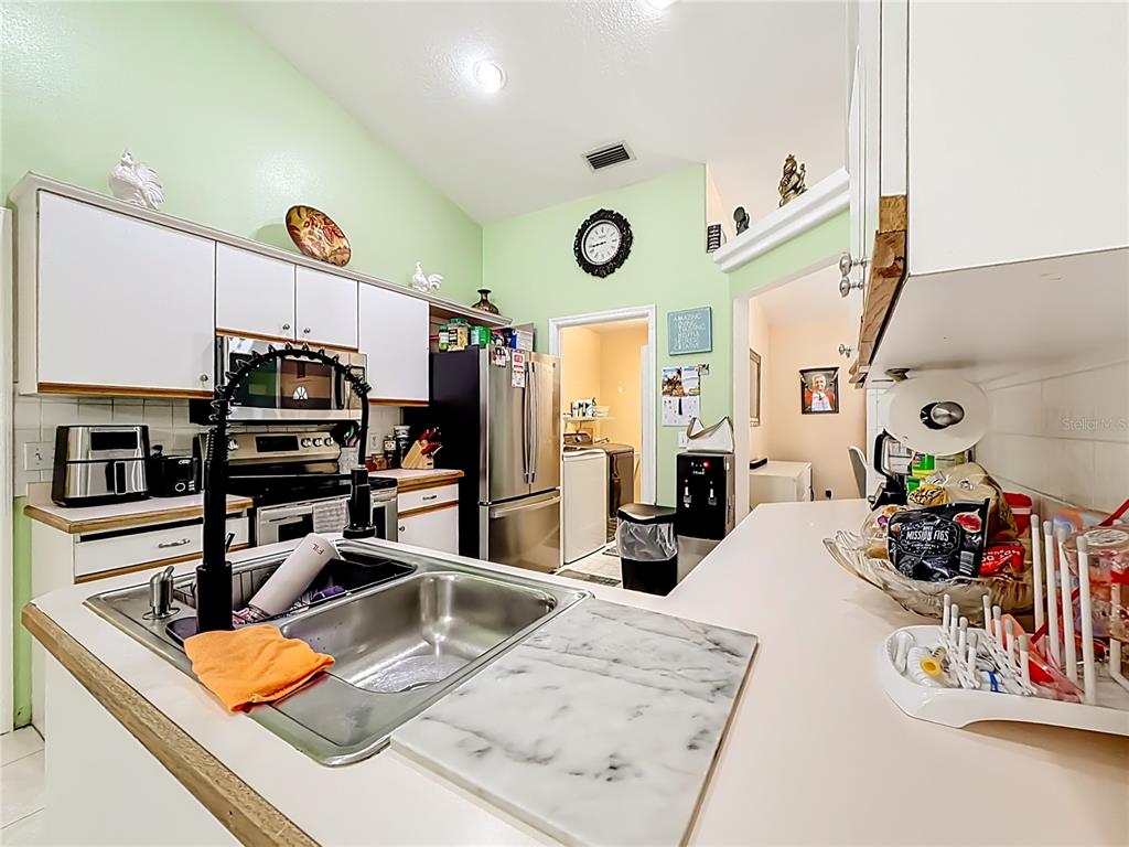 30 Hemlock Terrace Way Ocala, FL 34472 - Photo 17 of 44 a kitchen with stainless steel appliances kitchen island granite countertop a sink dishwasher stove and refrigerator with wooden floor