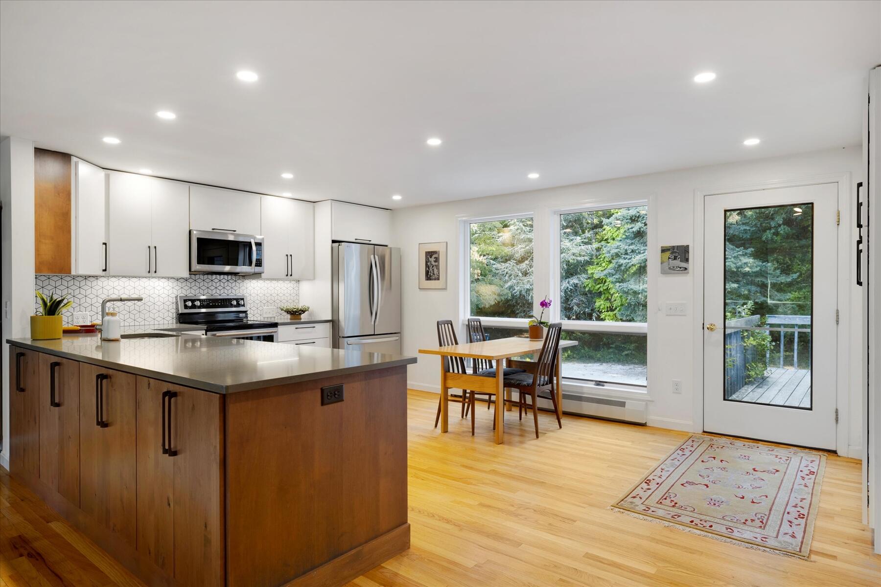 225 Coles Neck Road Wellfleet, MA 02667 - Photo 12 of 51 a kitchen with stainless steel appliances granite countertop a stove top oven a sink dishwasher a dining table and chairs with wooden floor