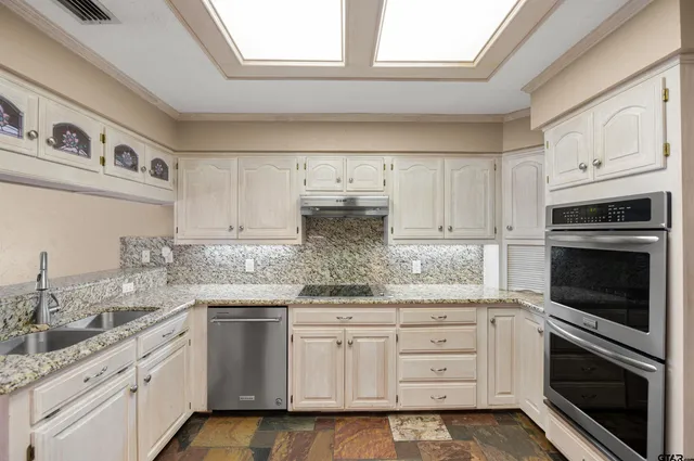 a kitchen with granite countertop white cabinets white stainless steel appliances and sink