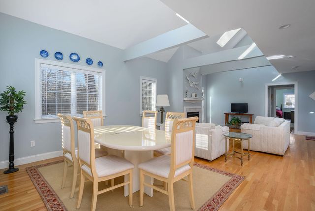 a dining room with wooden floor and large windows