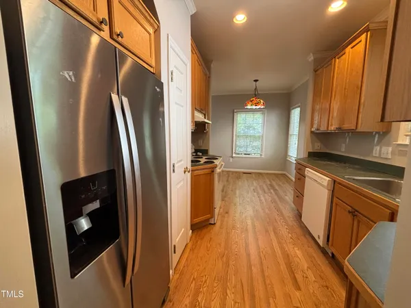 a kitchen with stainless steel appliances a refrigerator a sink a stove a microwave oven a refrigerator white cabinets and wooden floor