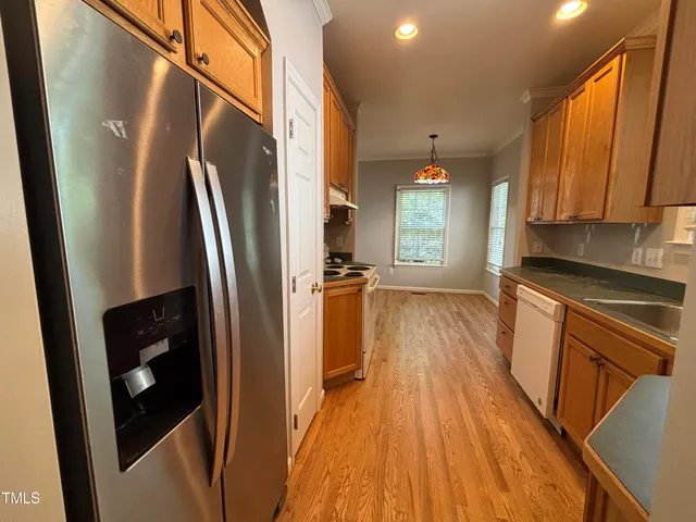 a kitchen with stainless steel appliances a refrigerator a sink a stove a microwave oven a refrigerator white cabinets and wooden floor