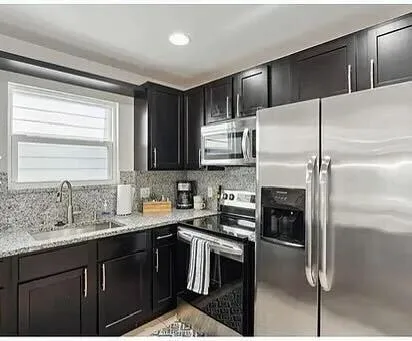 a kitchen with a sink stainless steel appliances cabinets and a window