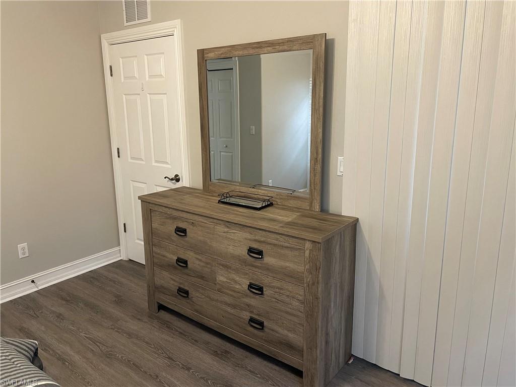 9195 Michael Circle, Unit 1301 Naples, FL 34113 - Photo 17 of 25 a room with a mirror and a wooden floor