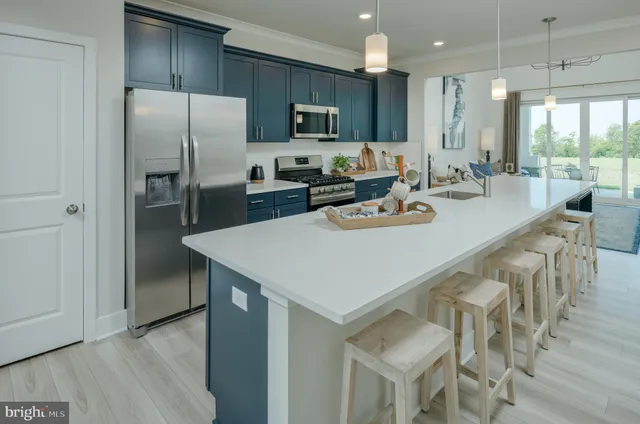 a kitchen with stainless steel appliances granite countertop a refrigerator a stove a sink a dining table and chairs