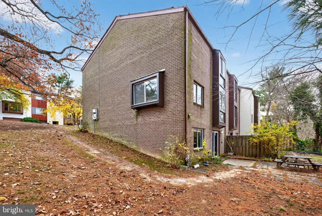 a backyard of a house with large trees and outdoor seating