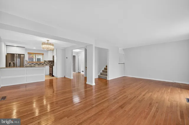 a view of an empty room with wooden floor and a fireplace