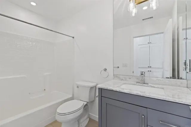 a bathroom with a granite countertop sink a toilet and shower