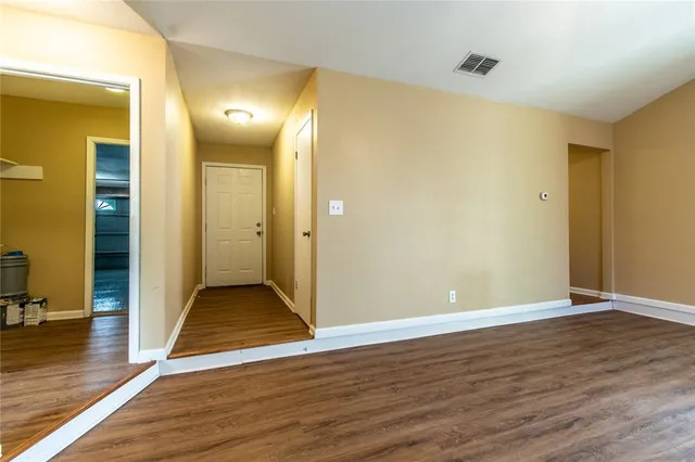 an empty room with wooden floor and entrance