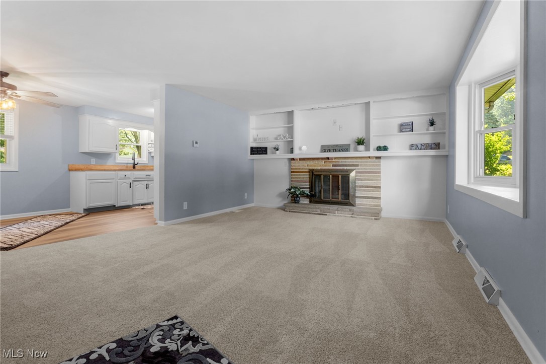 4895 3rd Street Northwest Canton, OH 44708 - Photo 6 of 27 Unfurnished living room with light colored carpet, ceiling fan, a fireplace, and built in features