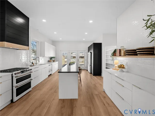 a large kitchen with stainless steel appliances kitchen island granite countertop a stove a sink and a refrigerator