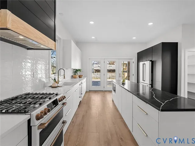 a large white kitchen with stainless steel appliances granite countertop a lot of counter space and wooden floors