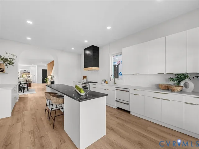a kitchen with white cabinets a sink dishwasher and a stove with wooden floor