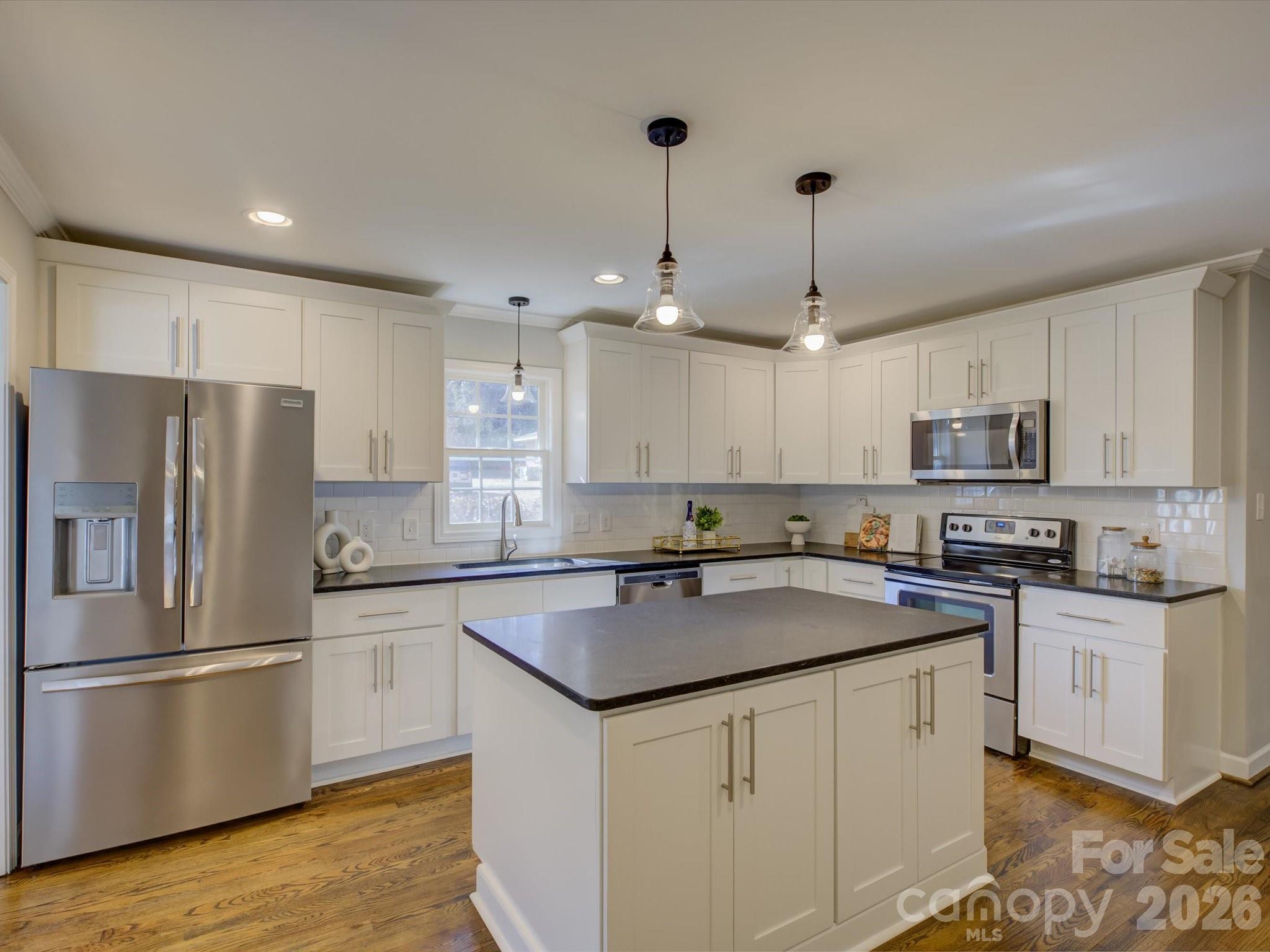 204 West Elliott Street Fort Mill, SC 29715 - Photo 10 of 43 a kitchen with stainless steel appliances granite countertop a sink stove a refrigerator and cabinets with wooden floor