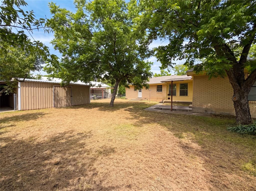 205 West Decatur Street Chico, TX 76431 - Photo 18 of 19 a backyard of a house with large trees and a wooden fence