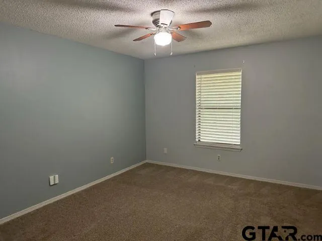an empty room with a window and a fan