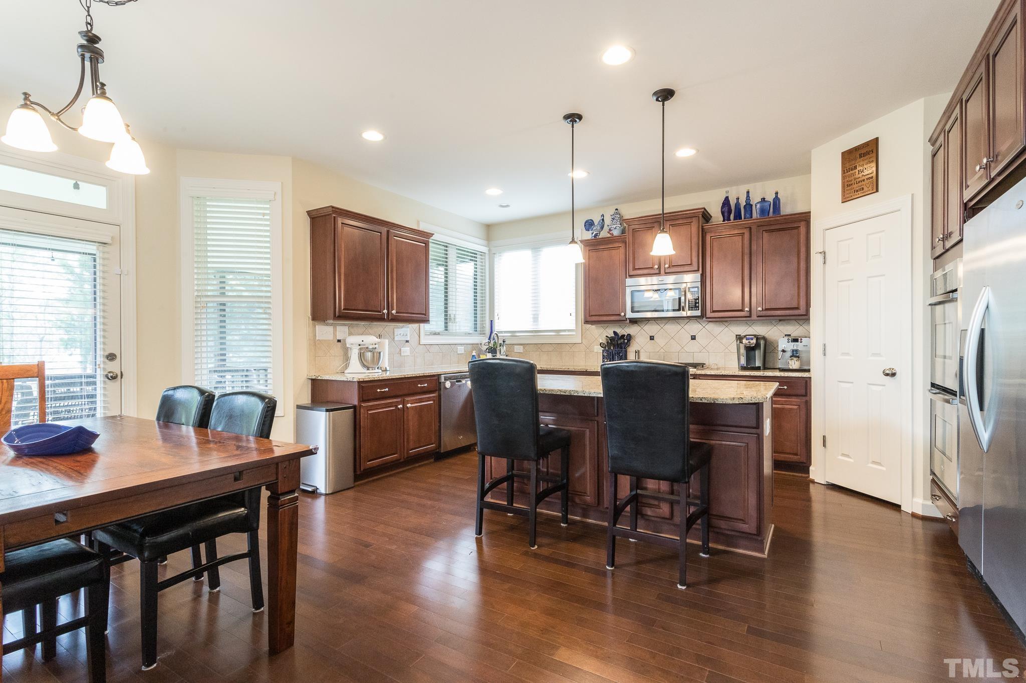 2800 Bending Tree Court Raleigh, NC 27613 - Photo 25 of 49 a kitchen with stainless steel appliances kitchen island granite countertop a dining table chairs and sink