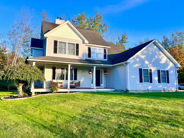 a view of a white house with a big yard and large trees
