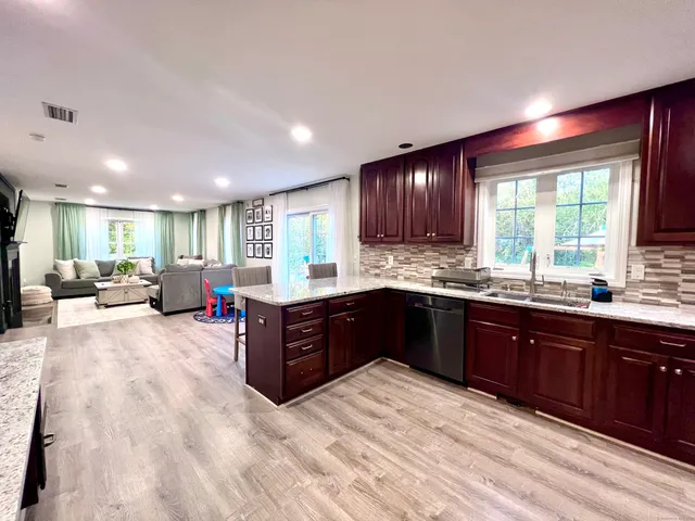 a large kitchen with stainless steel appliances granite countertop a refrigerator a sink dishwasher a dining table and chairs with wooden floor