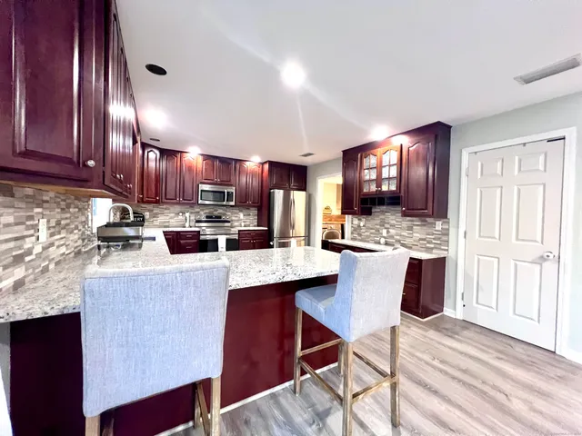 a kitchen with kitchen island granite countertop wooden cabinets stainless steel appliances a sink and a center island