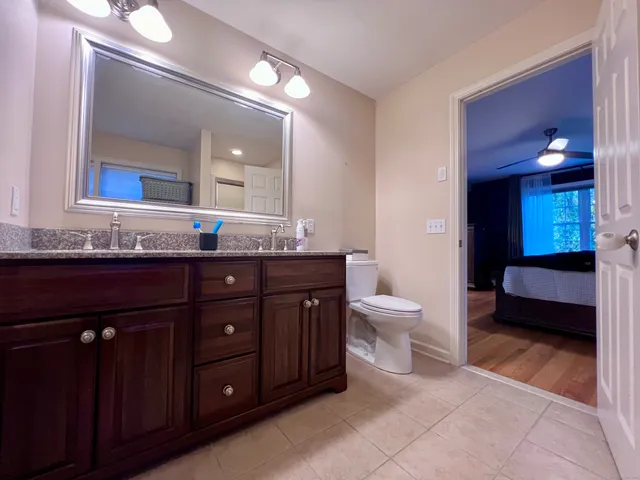 a bathroom with a granite countertop sink a toilet and a mirror