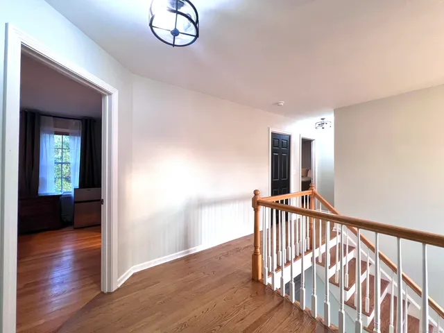 a view of a hallway with wooden floor and stairs