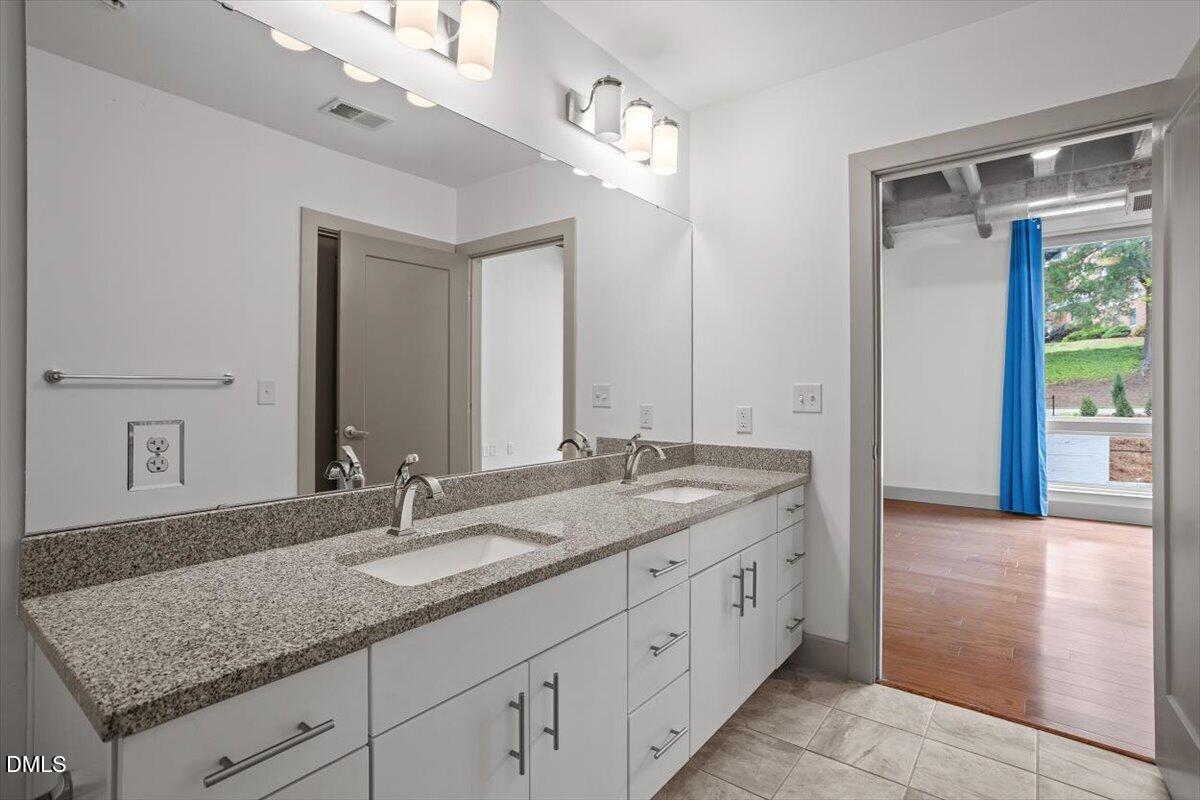 1300 St Marys Street, Unit 207 Raleigh, NC 27605 - Photo 13 of 31 a bathroom with a granite countertop double vanity sink and mirror