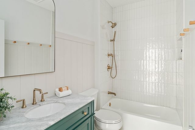 a bathroom with a granite countertop sink a toilet and shower