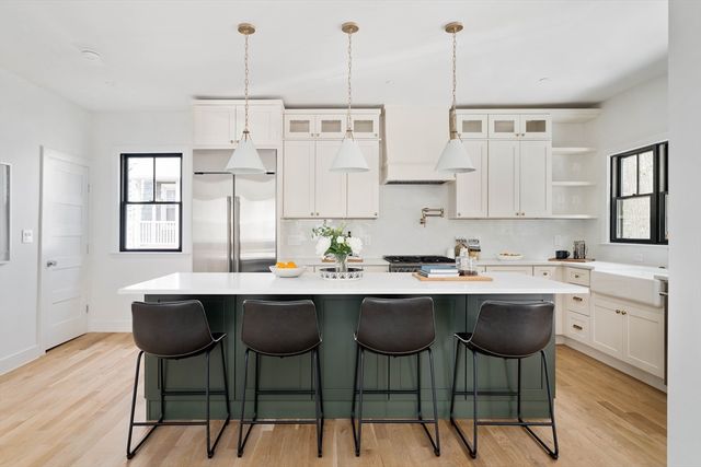 a kitchen with stainless steel appliances kitchen island a table chairs sink and cabinets