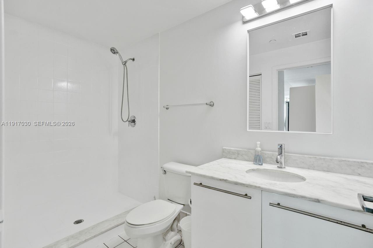 888 Biscayne Boulevard, Unit 2904 Miami, FL 33132 - Photo 18 of 27 a bathroom with a granite countertop sink a toilet and shower