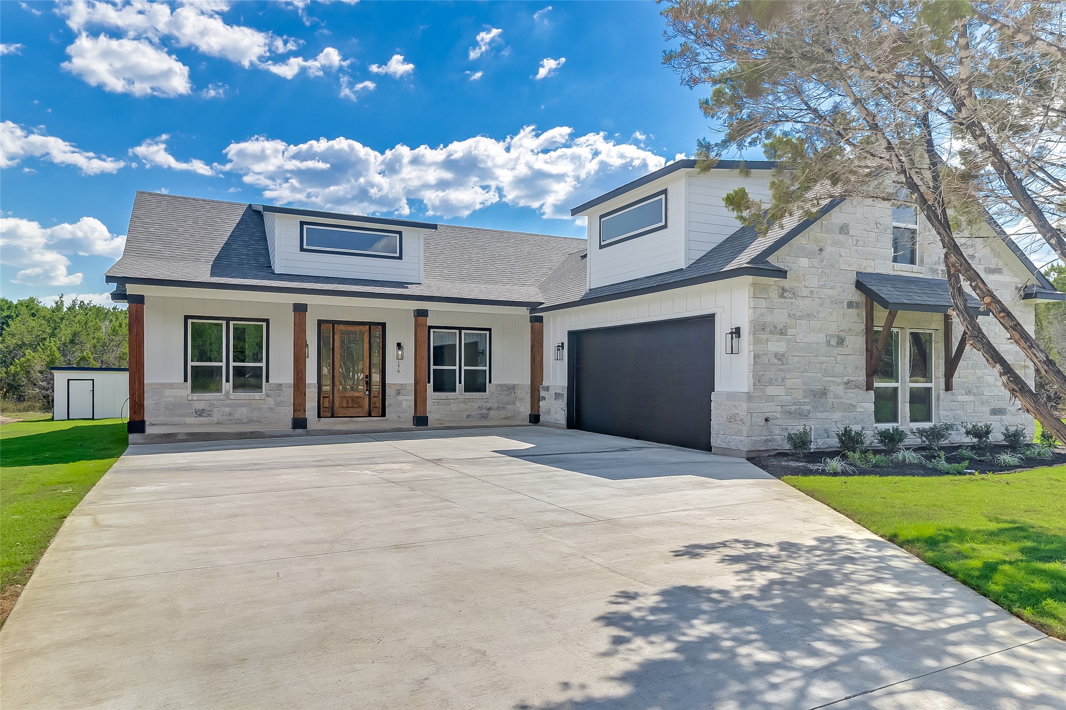 179 Rosebud Rnch Road Bertram, TX 78605 - Photo 1 of 1 View of front facade featuring stone siding, a shingled roof, concrete driveway, and a porch