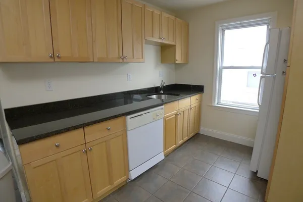 a kitchen with granite countertop a sink a stove and cabinets