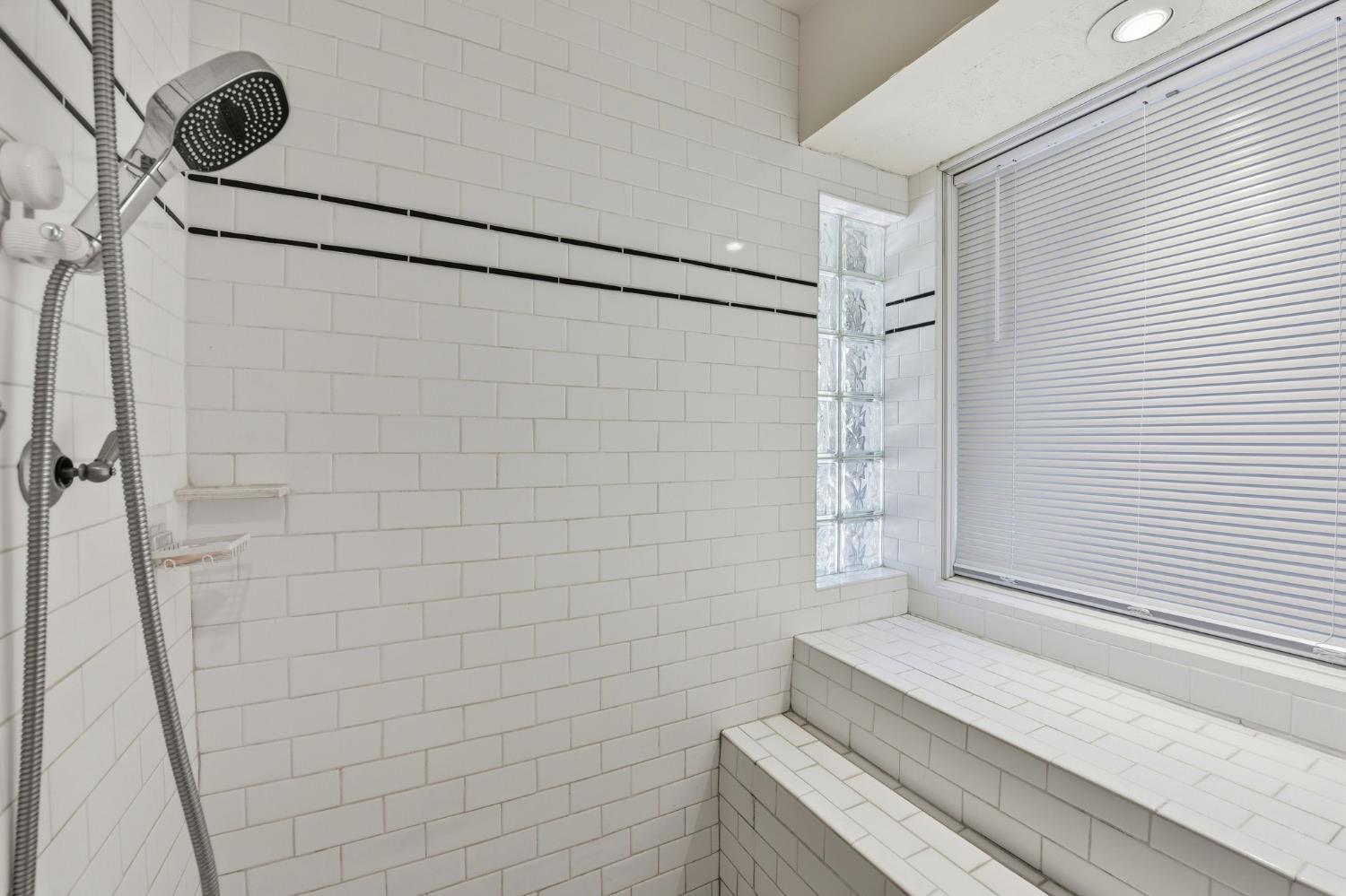 7201 Happy Valley Road Somerset, CA 95684 - Photo 27 of 75 The primary bathroom has a walk in shower with built in seating. Privacy glass block for privacy and light and a large window into the primary bedroom.