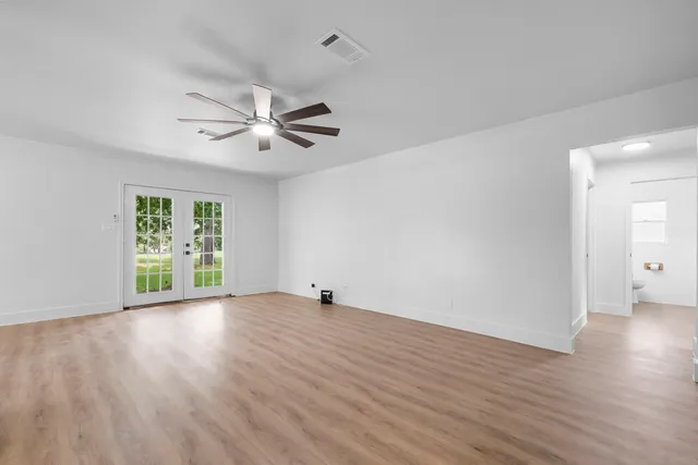 a view of an empty room with window and wooden floor