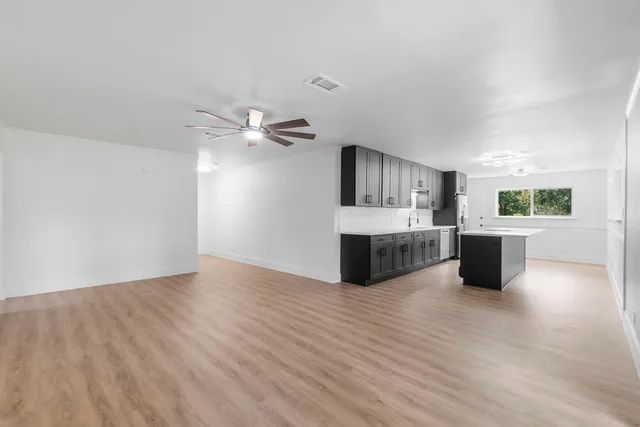 a view of a kitchen with an empty room and wooden floor