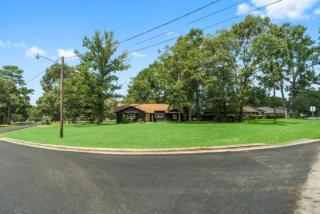 a view of a house with a big yard and large trees