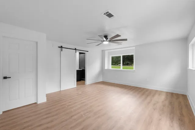 a view of an empty room with a window and wooden floor