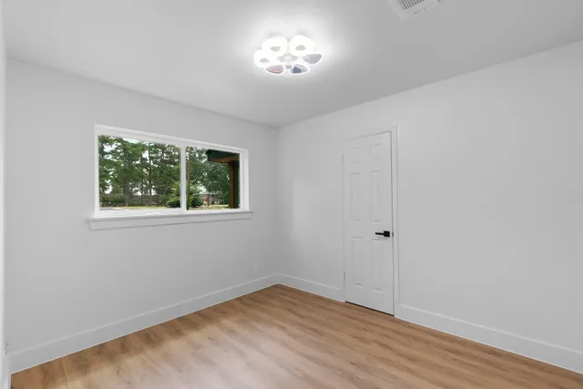 a view of an empty room with a window and wooden floor