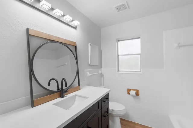 a bathroom with a sink a toilet and a mirror