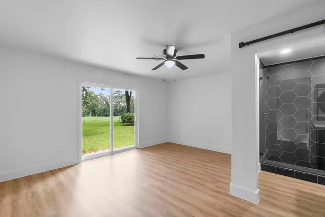 a view of an empty room with a window and wooden floor