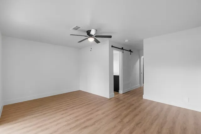 a view of a room with wooden floor and a ceiling fan