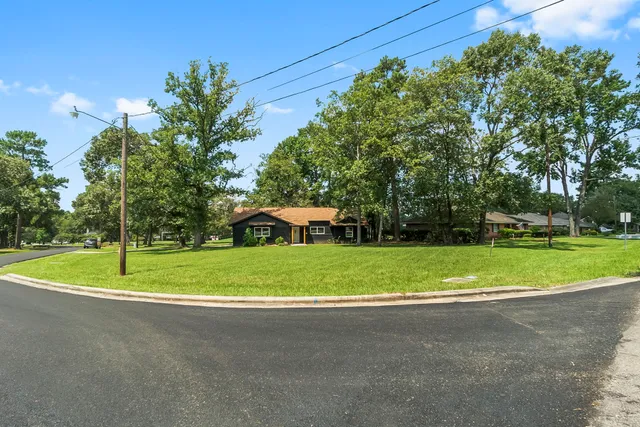 a view of a house with a big yard and palm trees