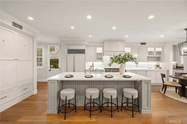 a dining room with wooden floor a chandelier a glass table and chairs
