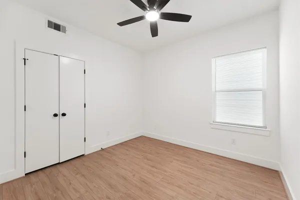 an empty room with wooden floor closet and windows